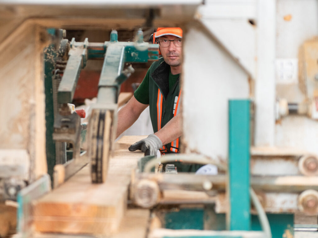 Employé de Denoyelle scierie vu de face en train de raboter une planche de bois